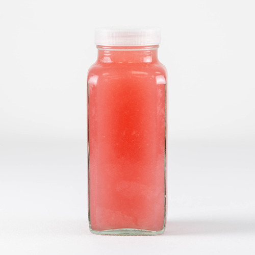 Glass bottle with a white cap containing pink/red juice against a white background, no label visible.